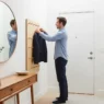 A man organizing a minimalist console table, demonstrating how to style a small apartment entryway with functional decor.